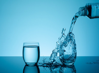 Bottle with creative splashing water in the glass