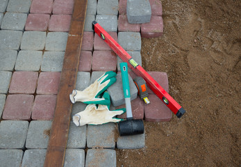  stone blocks rubber hammer level gloves and tape measure