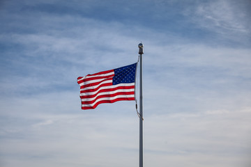 American flag waving in blue sky with clouds, USA