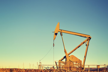 Fototapeta premium Vintage color toned an old oil pump at sunset, oil business concept, copy space.