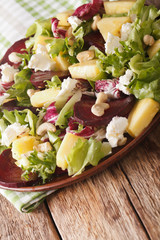 Fresh salad of beets, pineapple, goat cheese, cashews and greens mix closeup. vertical