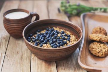Oatmeal porridge with blueberries, milk and cookies, healthy food concept