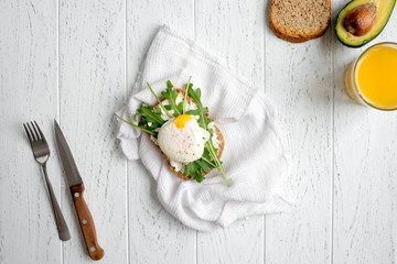 sandwich with poached eggs on wooden background top view