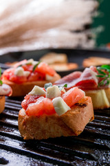 Close up of set of bruschetta on black grill background. Tasty antipasto.