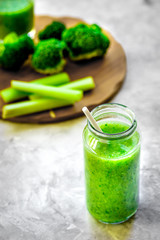 Green vegetable smoothie in glass at gray background