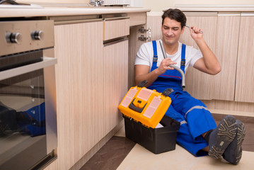 Young repairman working at the kitchen