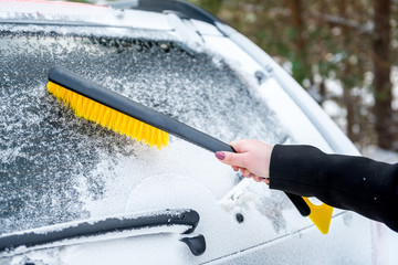 Woman cleaning car from snow with brush. Transportation, winter,