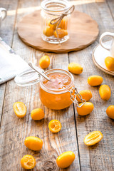 kumquat on plate and jam in jar at wooden table