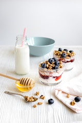 Cooking breakfast with granola and berries on white kitchen background