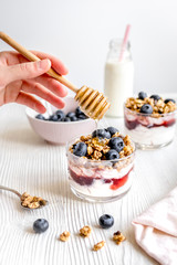 Cooking breakfast with granola and berries on white kitchen background