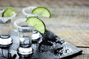 Party in bar with tequila, salt and lime on wooden table
