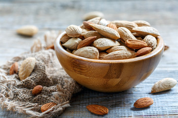 Almonds in a wooden bowl and old sacking.