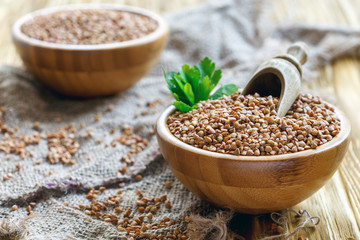 Wooden bowl of buckwheat, sprig of parsley and scoop.