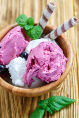 Vanilno-berry ice cream with wafer rolls in a wooden bowl.