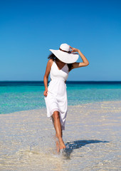 Fototapeta na wymiar Frau in weißem Kleid läuft auf einer Sandbank auf den Maldeiven