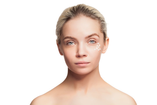 Young woman with cream drops on face on white background