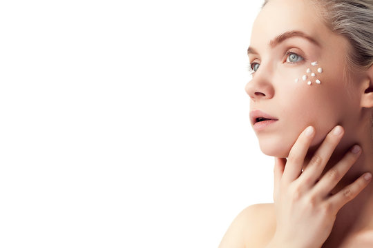 Beautiful woman with cream drops on face on white background