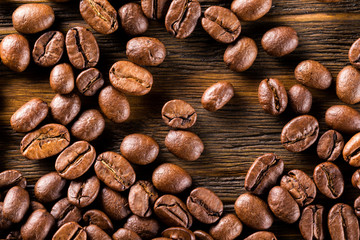 Macro image of roasted coffee beans at brown textured wooden boa