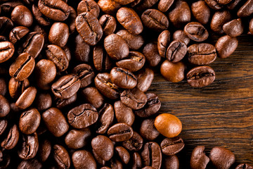 Macro image of roasted coffee beans at brown textured wooden boa