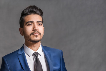 Young attractive man in a blue suit on a gray background