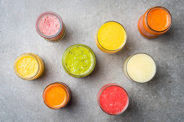 Glasses of fresh juice on gray stone table. Food background