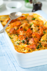 Baked pumpkin with chicken, spices and cream sauce in a white ceramic form on a light background. Selective focus.
