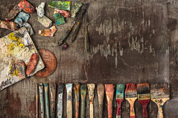 paint brushes and tubes of oil paints on wooden background