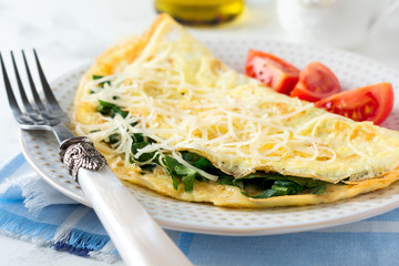 Omelet with spinach, parsley and cheese for breakfast on a light background. Selective focus.