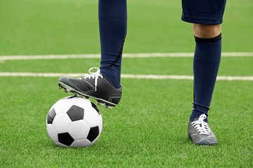 Football player holding ball with foot, closeup