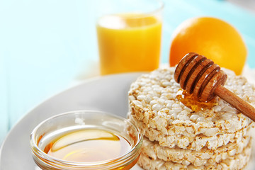 Closeup of tasty rice wafers with honey and glass of orange juice