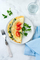 Omelet with spinach, parsley and cheese for breakfast on a light background. Selective focus.