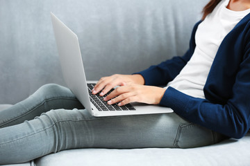 Cute girl sitting on sofa with laptop, closeup