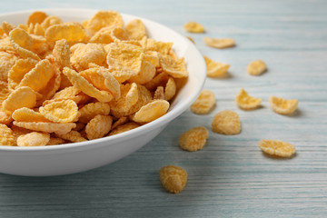 Bowl with cornflakes on white wooden background, closeup