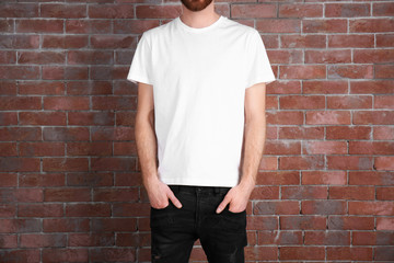Closeup of man in white T-shirt on brick wall background