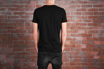 Closeup of man in black T-shirt on brick wall background