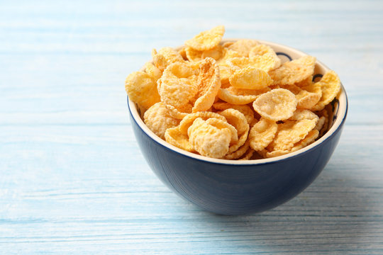 Bowl with cornflakes on white wooden background