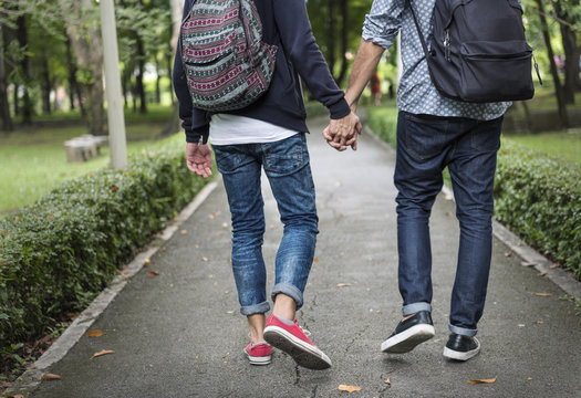 Low section of couple holding hands walking on road