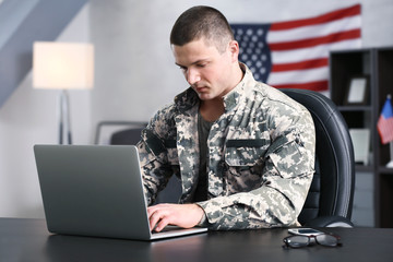 Soldier working with laptop in headquarters building