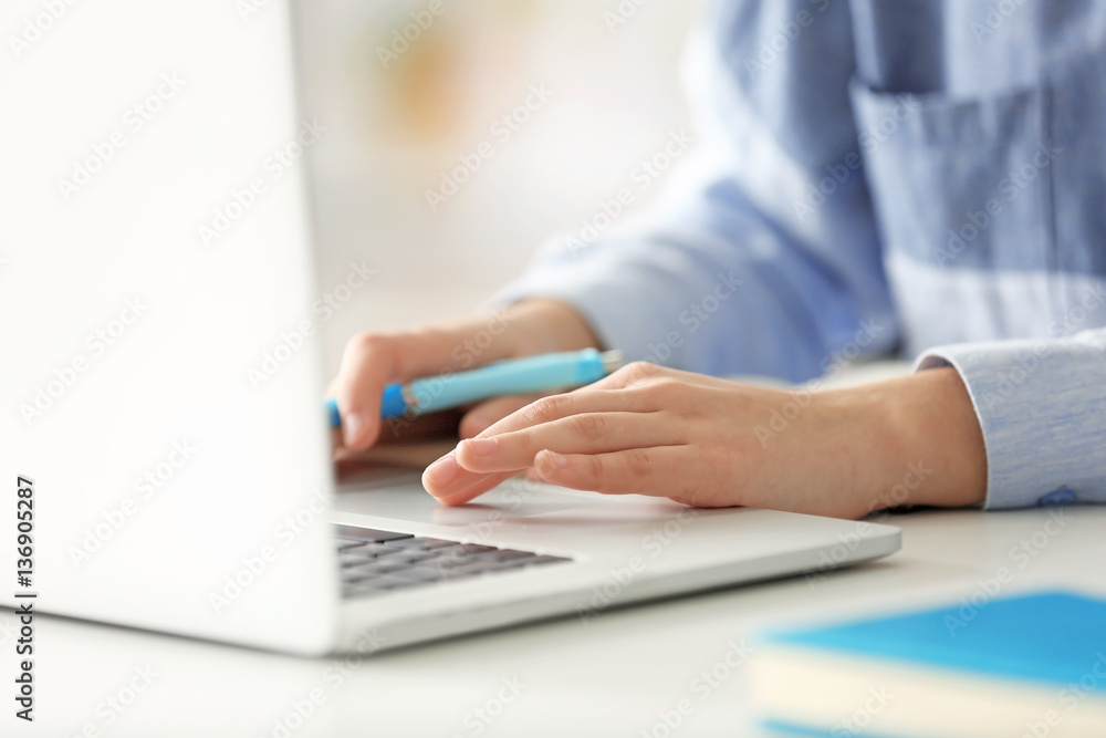 Wall mural Young woman working in office with laptop, closeup