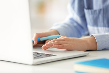Fototapeta premium Young woman working in office with laptop, closeup