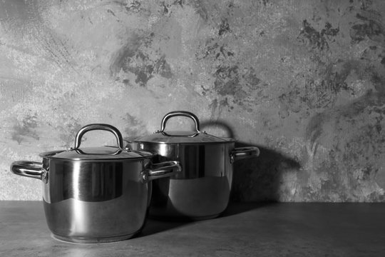 Metal pans with lids on textured wall background
