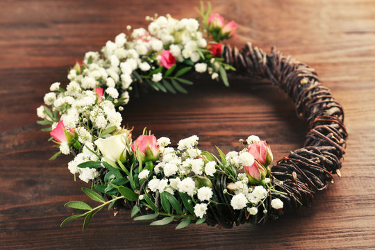 Floral wreath with beautiful flowers on wooden background