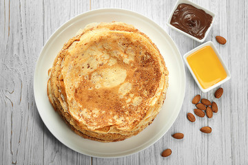 Plate with tasty pancakes on white wooden table