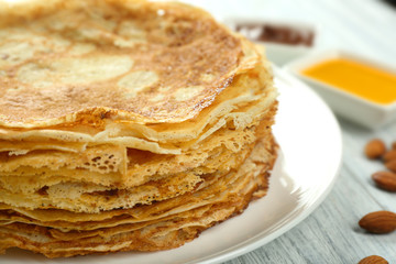 Plate with tasty pancakes on white wooden table, closeup