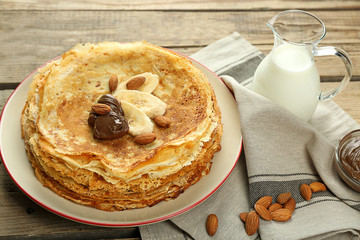 Delicious pancakes with banana and chocolate on wooden table