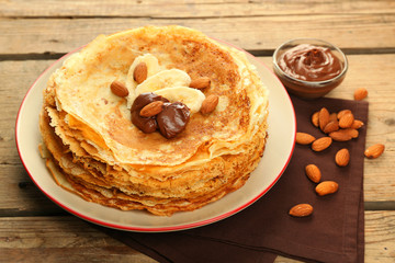 Delicious pancakes with banana and chocolate on wooden table