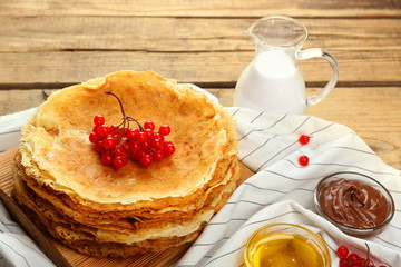 Delicious pancakes decorated with viburnum on wooden board