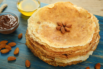 Stack of tasty pancakes decorated with almonds on blue wooden board
