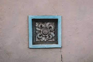Rosette on the stone grey wall with flowers, architecture of street of Asia