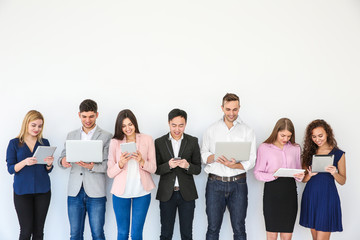 Obraz premium People with gadgets standing near light wall